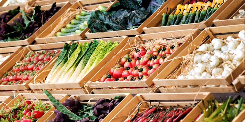 Display of assorted farm fresh vegetables on a market stall or in a store neatly arranged in rows in wooden boxes